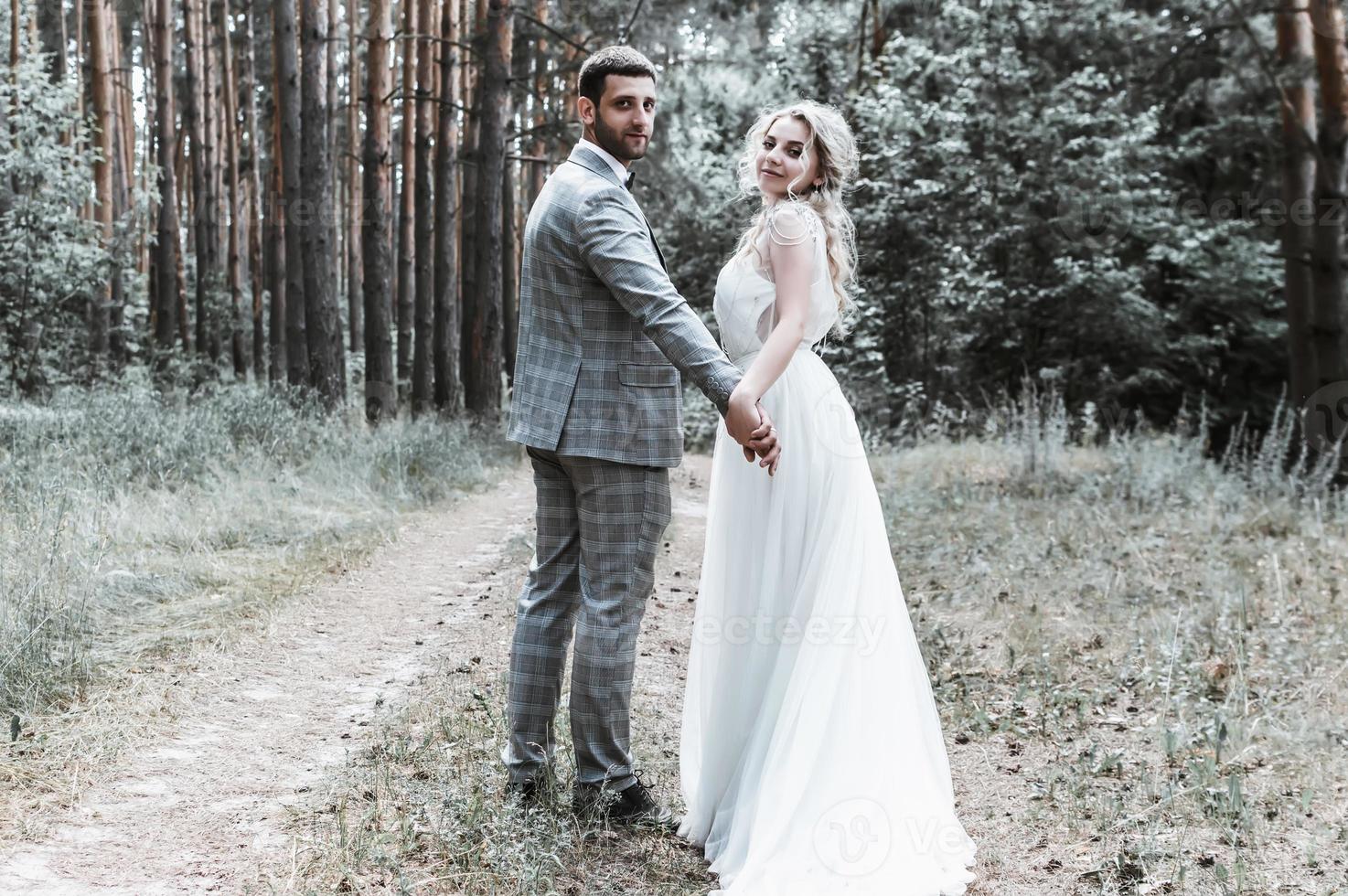 gli sposi si abbracciano nella foresta il giorno del matrimonio. cerimonia matrimoniale. messa a fuoco selettiva. grana della pellicola. foto