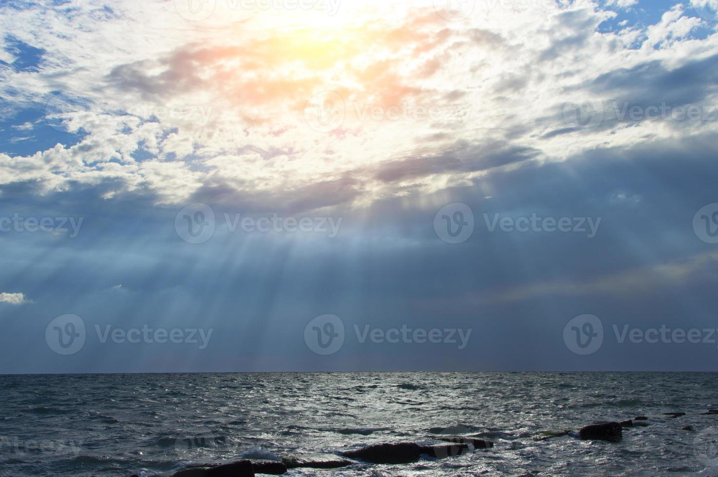 calmo paesaggio marino con cielo tempestoso dove i raggi del sole attraversano le nuvole. foto