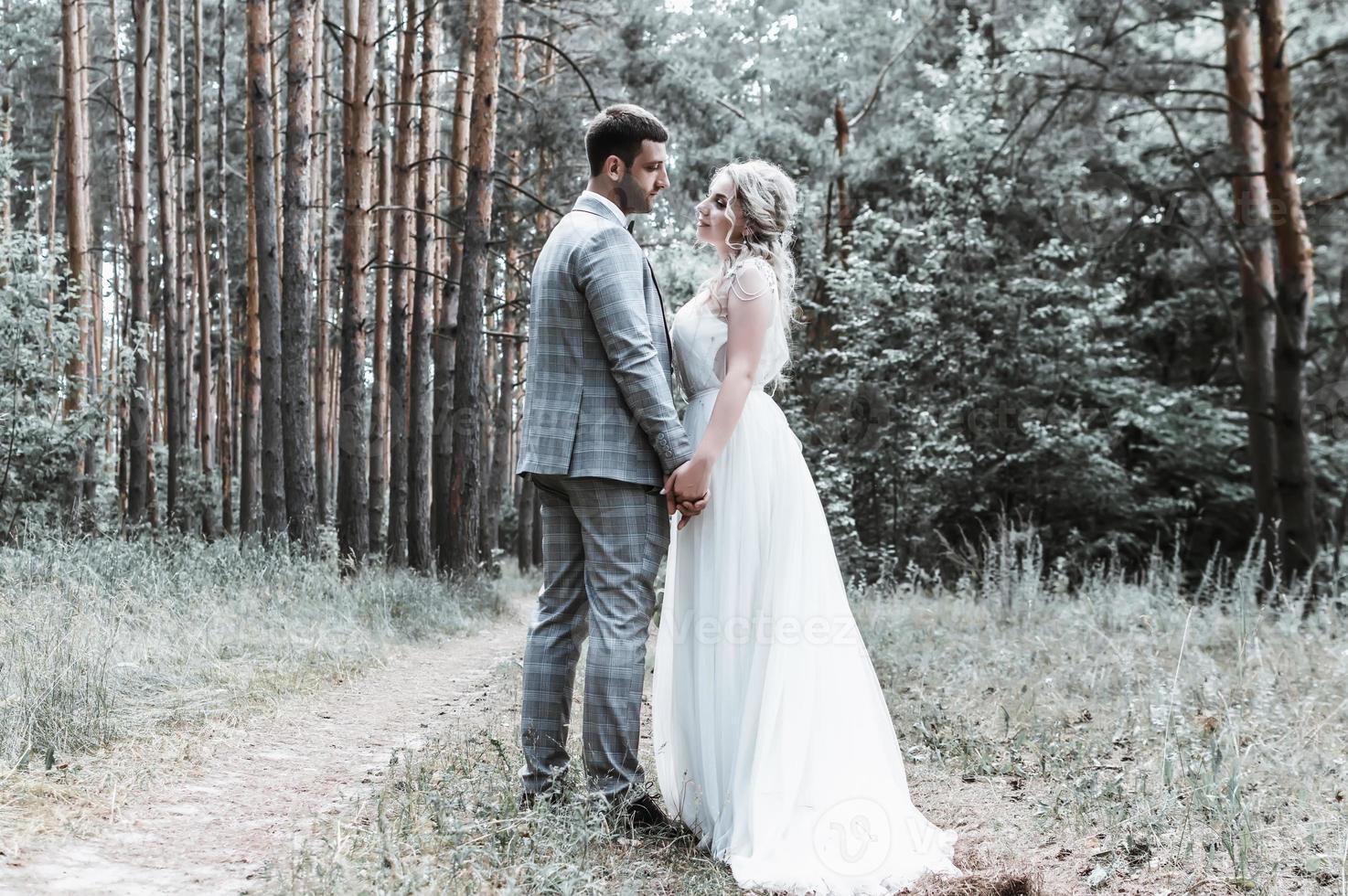 gli sposi si abbracciano nella foresta il giorno del matrimonio. cerimonia matrimoniale. messa a fuoco selettiva. grana della pellicola. foto