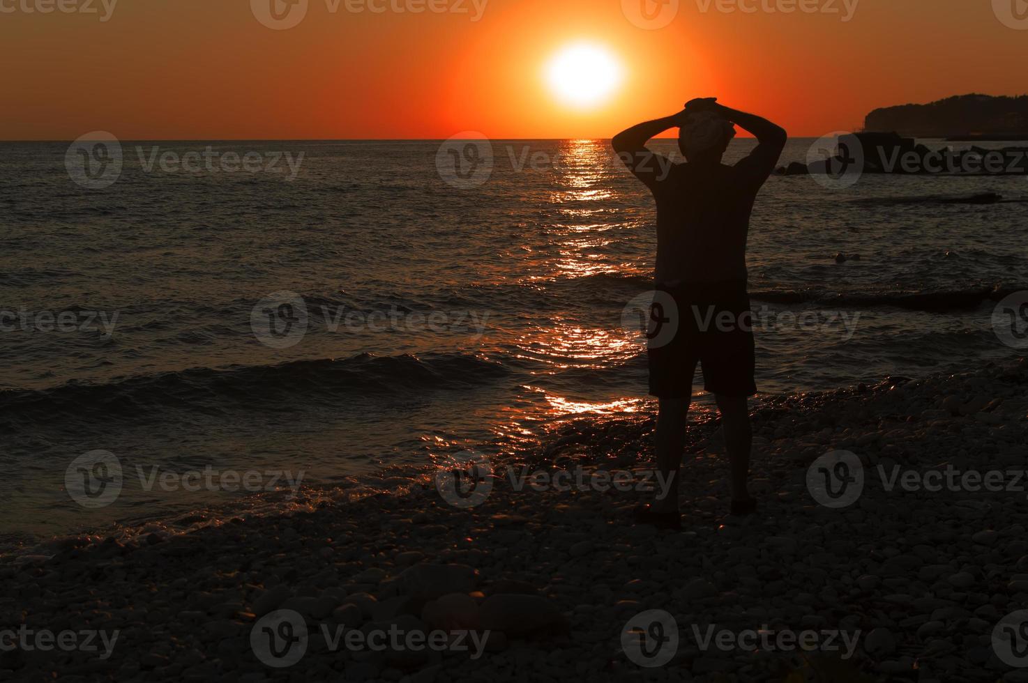 la sagoma di un uomo sullo sfondo di un tramonto in riva al mare. la solitudine. foto