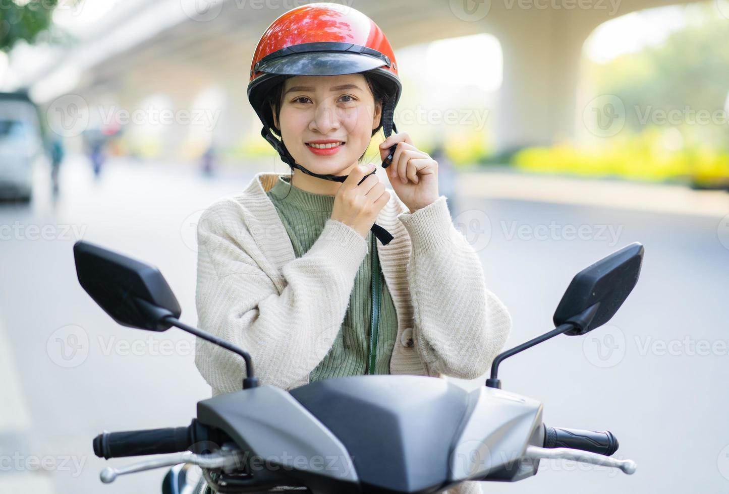 donna asiatica che guida una moto mentre va al lavoro foto