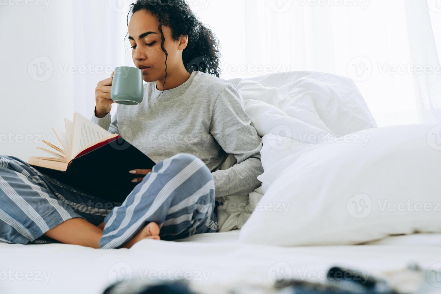 donna africana seria che beve caffè e legge un libro foto