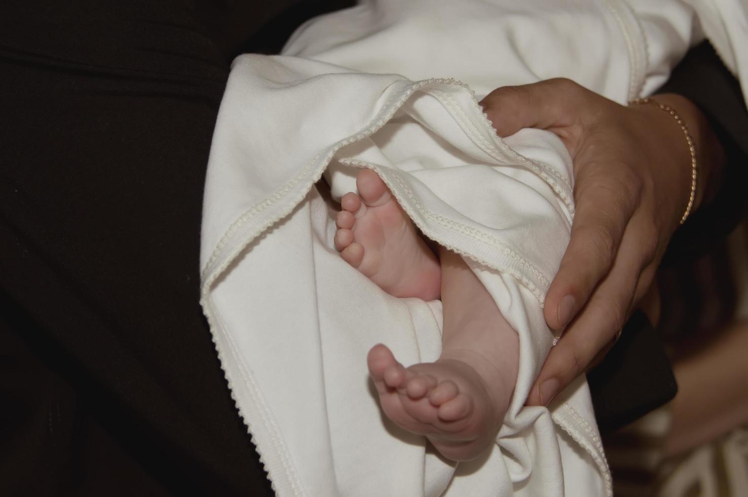 le gambe del bambino in chiesa alla cerimonia del battesimo. religione. avvicinamento. foto