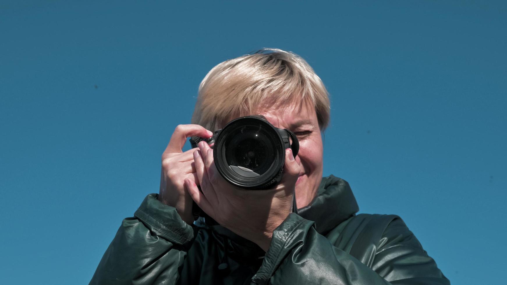 una ragazza fotografa scatta una foto del cielo azzurro su una macchina fotografica e guarda direttamente nella macchina fotografica