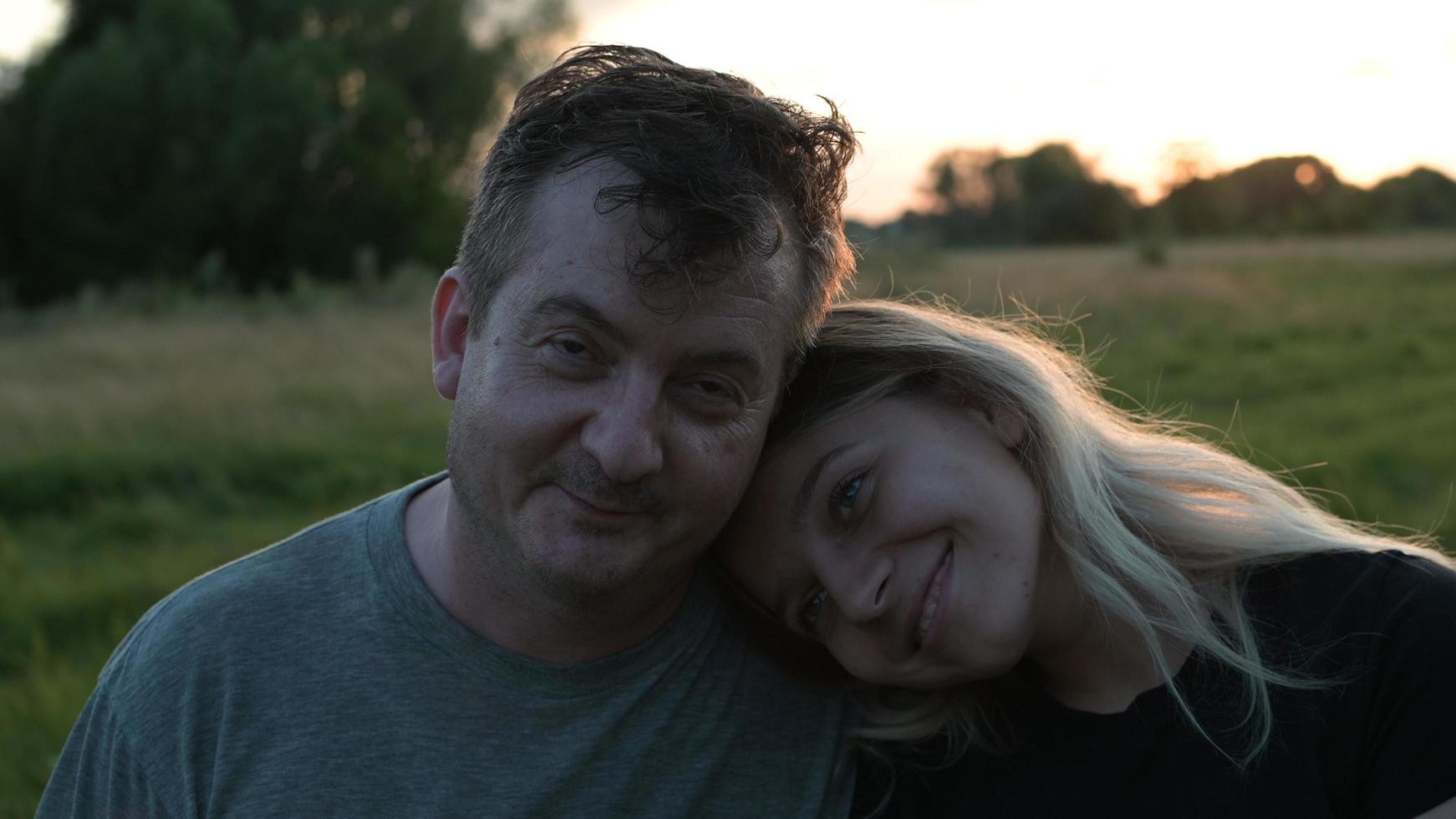 papà e figlia bionda adulta sono seduti in un abbraccio sullo sfondo della natura autunnale al tramonto foto