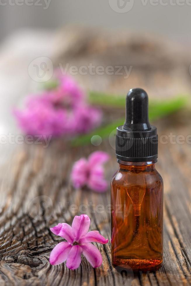 bottiglia di olio essenziale di giacinto rosa e fiore su sfondo di legno foto