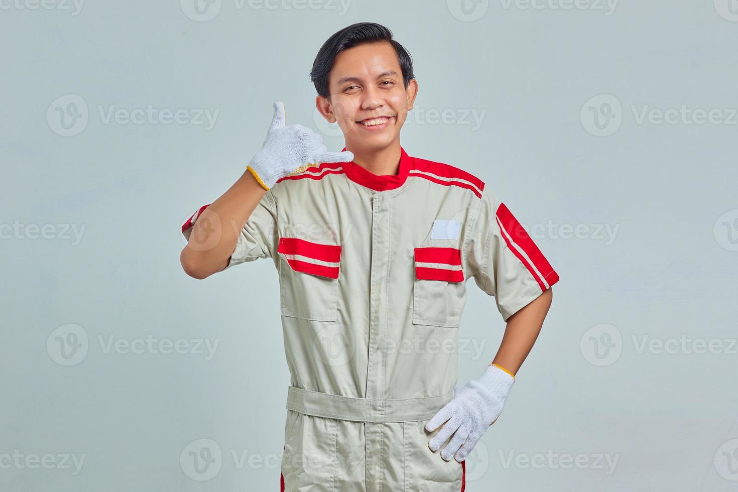 ritratto di un bell'uomo allegro che indossa un'uniforme meccanica che mostra approvazione con il gesto del pollice in alto su sfondo grigio foto