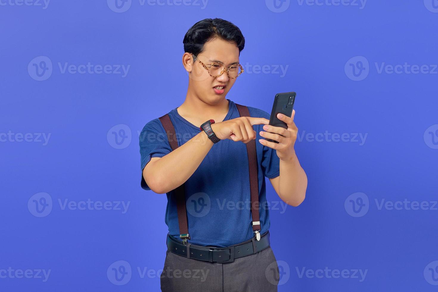 giovane confuso su come utilizzare il telefono cellulare per aprire i social media con uno spazio vuoto su sfondo viola foto