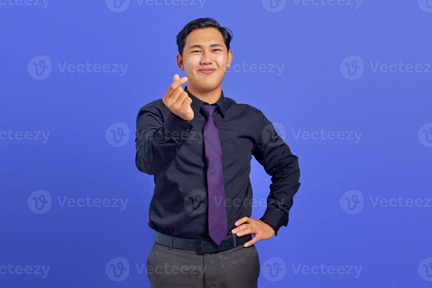 sorridente giovane uomo asiatico che mostra gesto di amore segno su sfondo viola foto