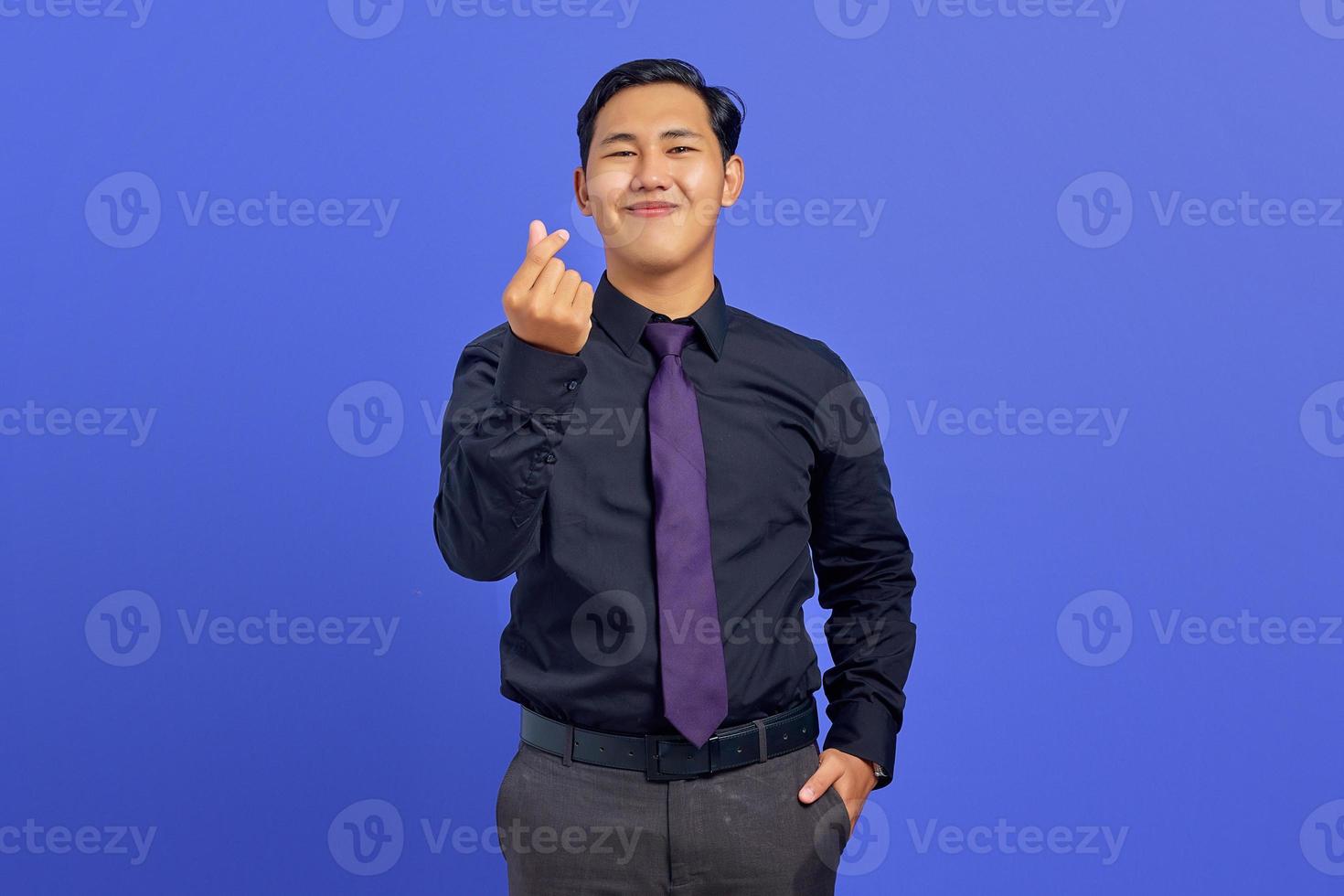 sorridente giovane uomo asiatico che mostra gesto di amore segno su sfondo viola foto