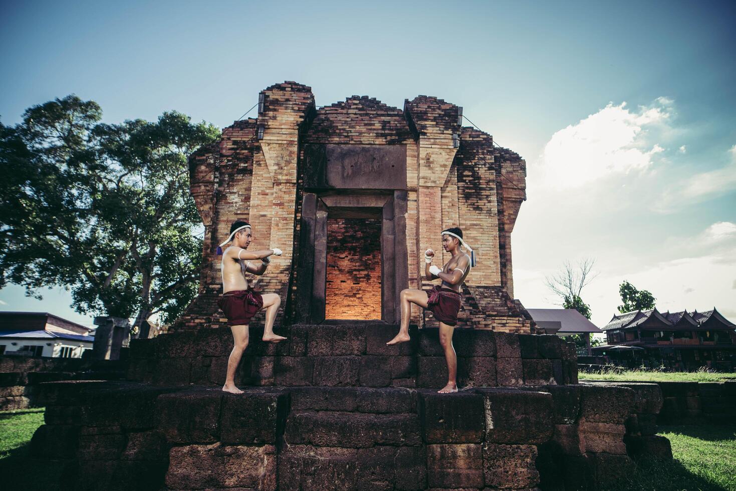 i pugili tailandesi avvolgono il nastro nelle loro mani e stanno in piedi sulla pietra davanti alla porta. foto