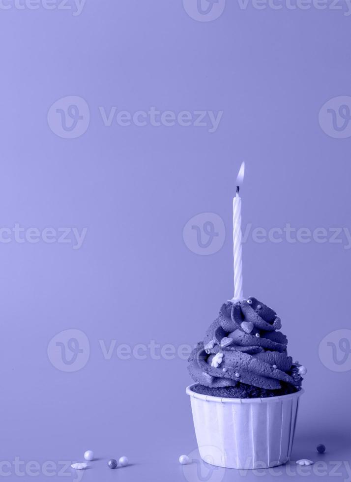 cupcake a forma di albero di natale con una candela su uno sfondo dai toni molto peri foto