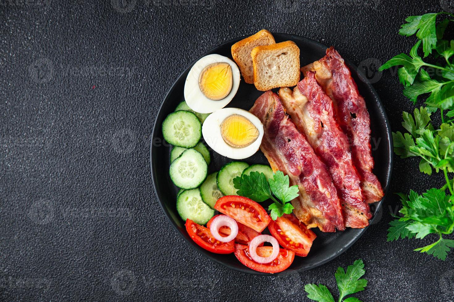 colazione inglese bacon, uova, pomodoro, cetriolo, pane tostato foto