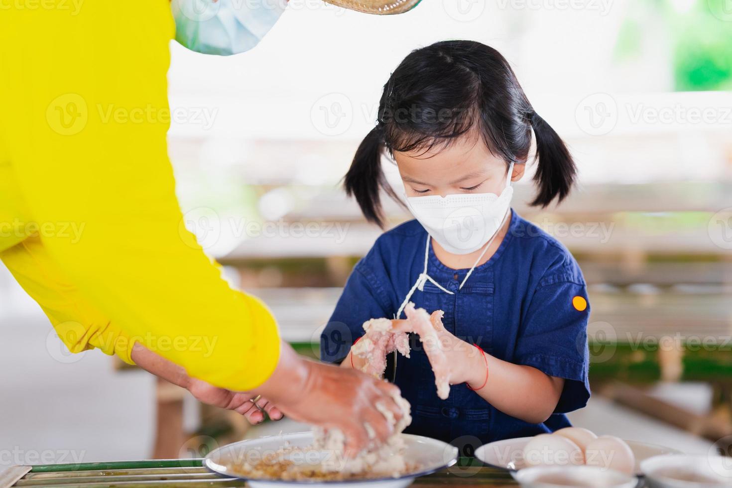 un contadino insegna a un bambino in età prescolare a preparare uova salate con polvere di argilla bianca mescolata con sale e acqua. le persone che indossano la maschera per il viso prevengono l'inquinamento da polvere pm2.5 e coronavirus covid19. foto