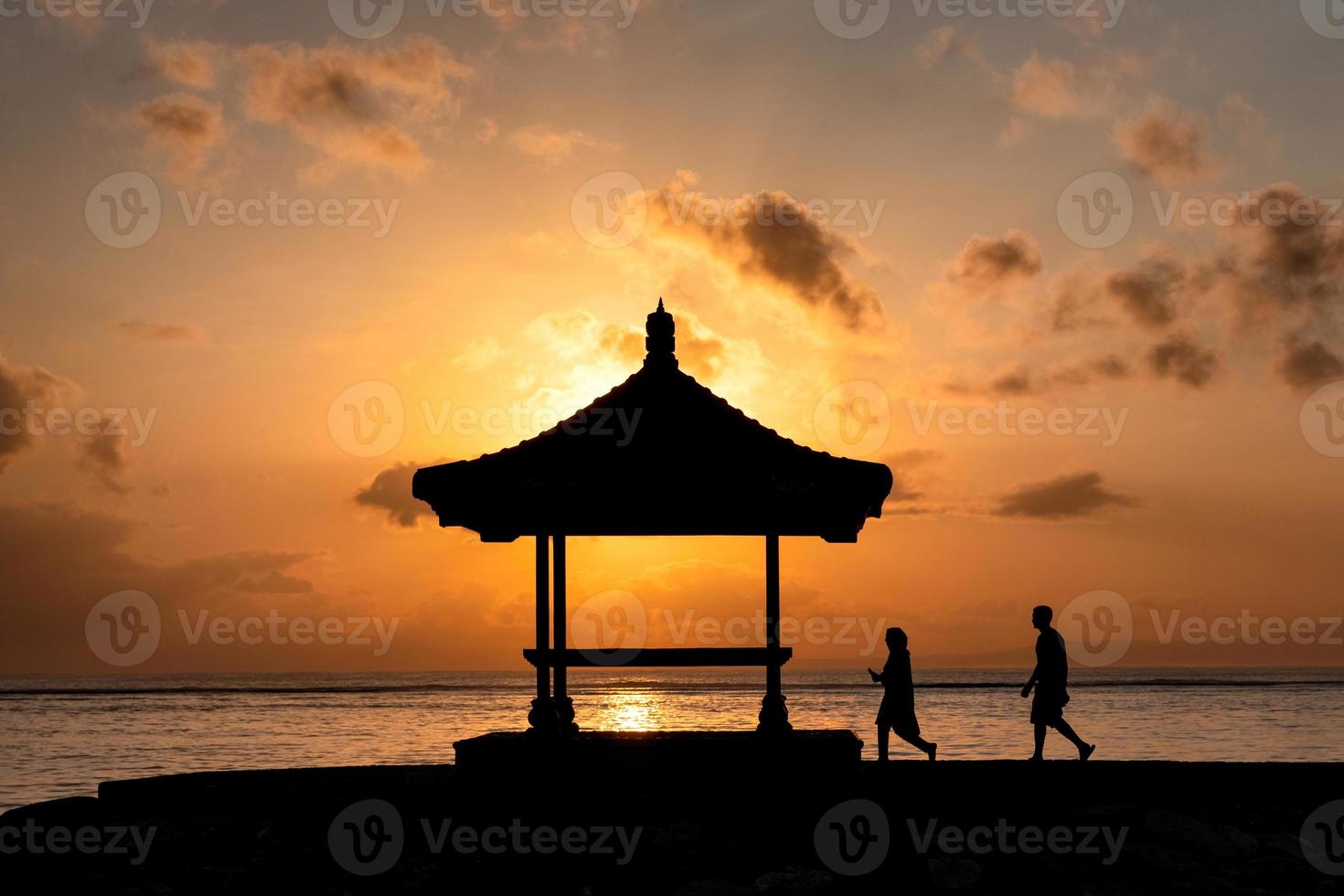 coppia di silhouette che cammina verso il padiglione con l'alba che splende foto