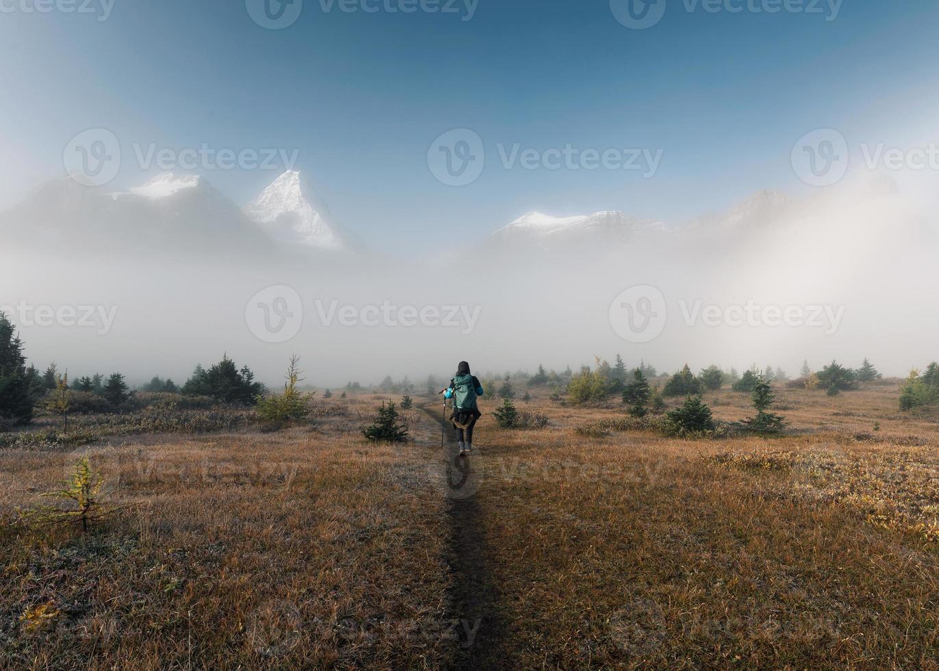 uomo zaino in spalla trekking sul campo con montagne rocciose nella nebbia al parco provinciale foto