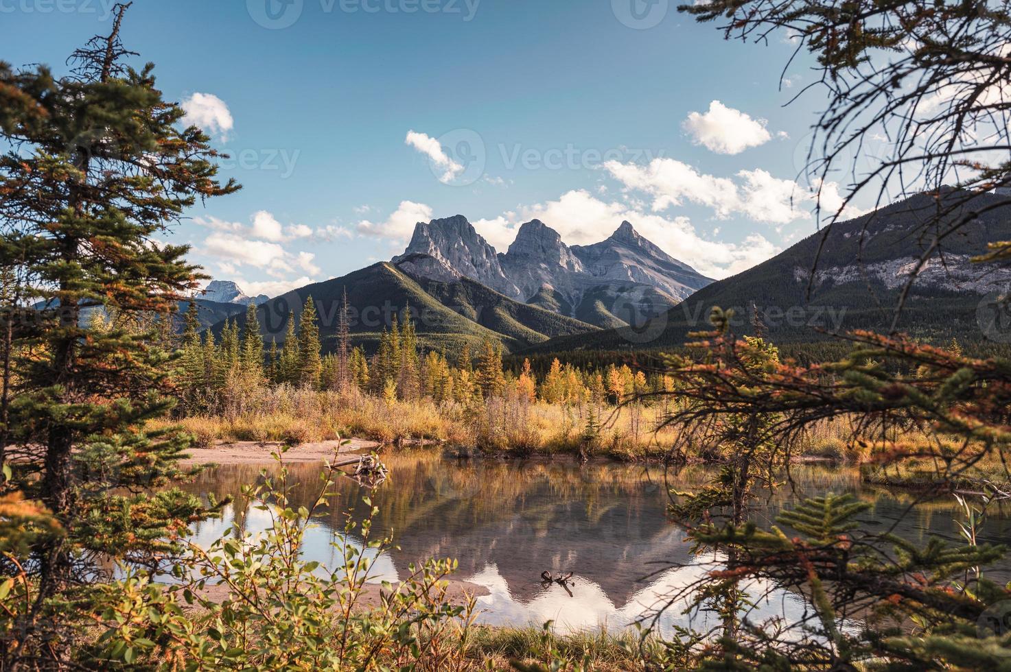 tre sorelle montagne nella riflessione della foresta autunnale sullo stagno a canmore, canada foto