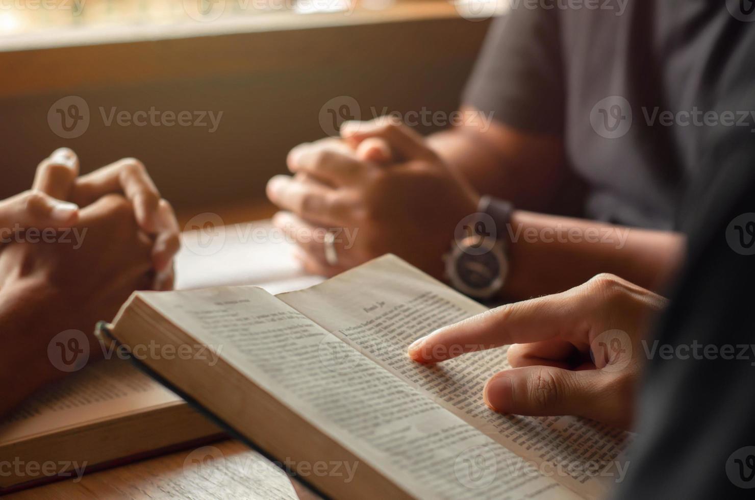 giovane che legge la Bibbia con gli amici che stanno pregando Dio si uniscono al gruppo di cellule in chiesa. un piccolo gruppo di cristiani o concetti in una chiesa in una chiesa. foto