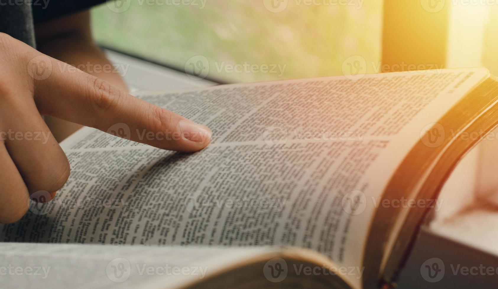 una giovane donna che indica i versetti delle Scritture che sono veritieri. mentre leggevo la Bibbia al mattino vicino al davanzale della finestra foto