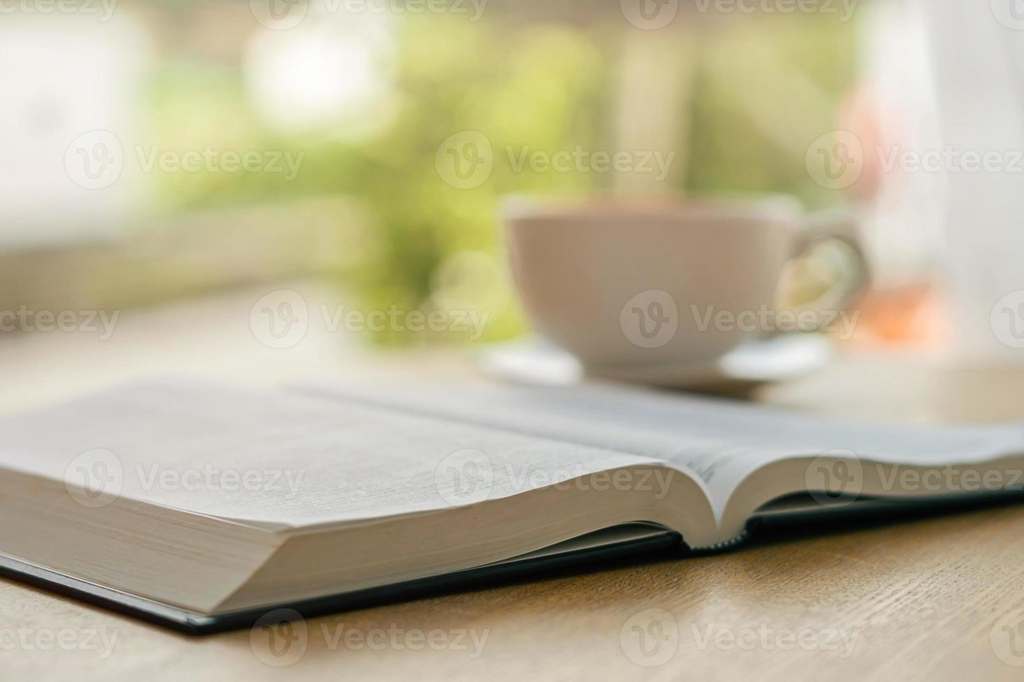 Bibbia aperta con una tazza di caffè bianca con l'atmosfera mattutina su un tavolo di legno vicino al davanzale della finestra foto