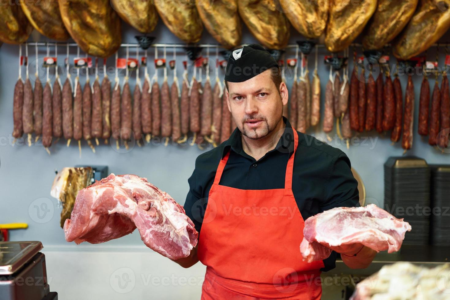 macellaio che tiene la carne in piedi in una macelleria foto