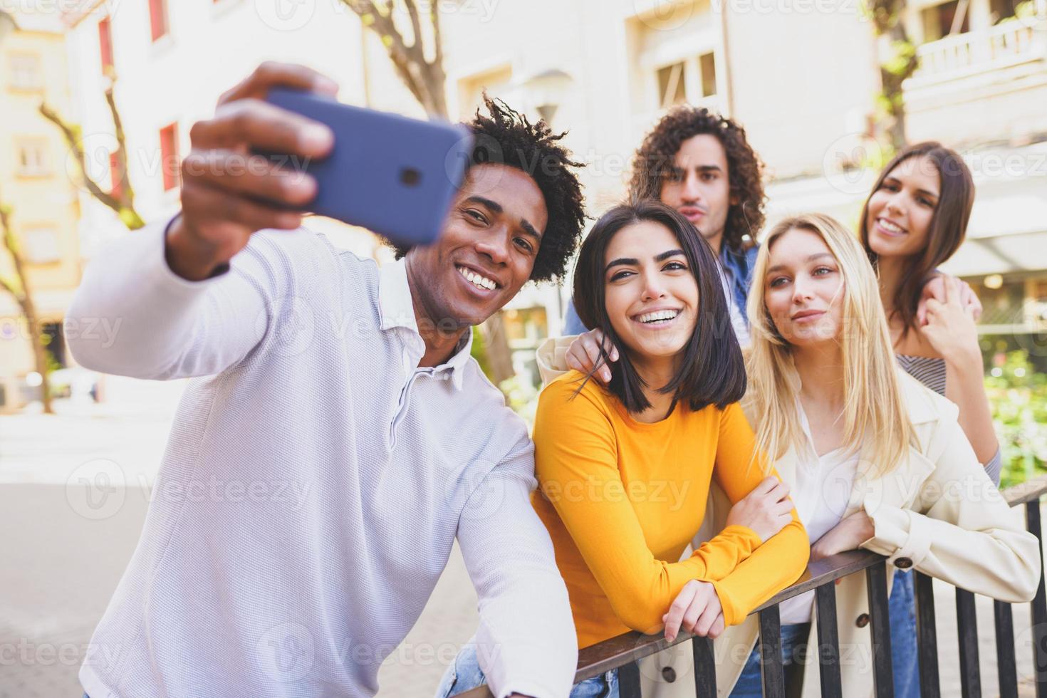 gruppo multietnico di amici che si fanno un selfie in strada con uno smartphone. foto