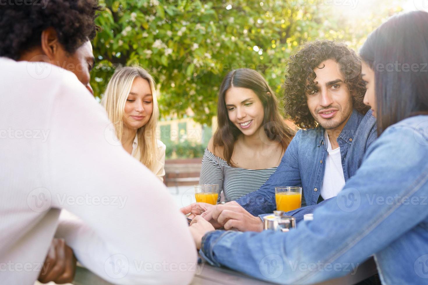 gruppo multietnico di amici che bevono insieme in un bar all'aperto. foto