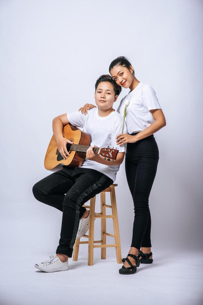 due giovani donne si sedevano su una sedia e suonavano la chitarra. foto