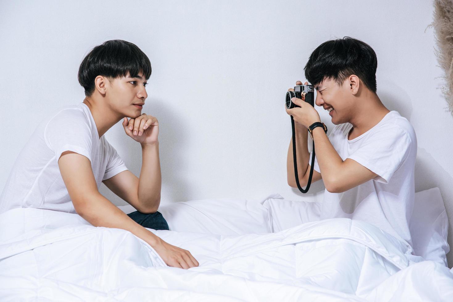 due amati giovani si sono seduti sul letto e hanno scattato foto con la macchina fotografica.