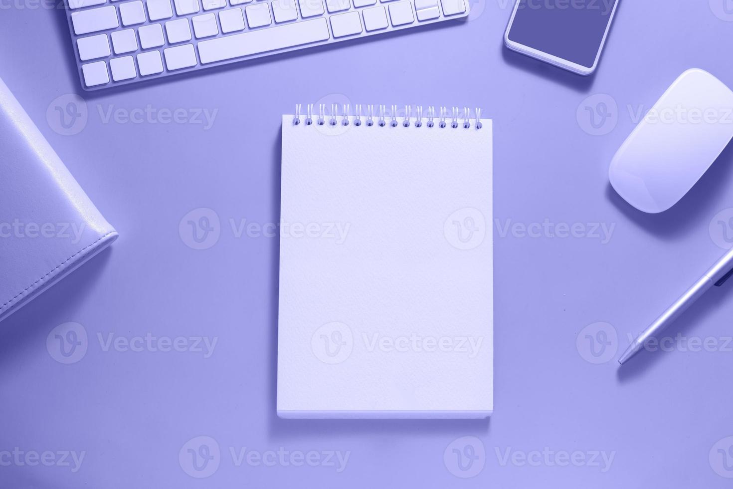 vista dall'alto del desktop con tastiera, mouse e taccuino vuoto su sfondo a colori molto peri. concetto di obiettivi e piani aziendali per il nuovo anno foto