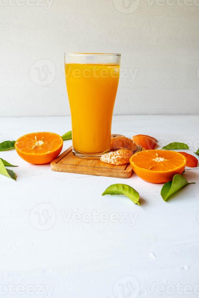 succo d'arancia e frutta fresca d'arancia su uno sfondo di legno bianco foto