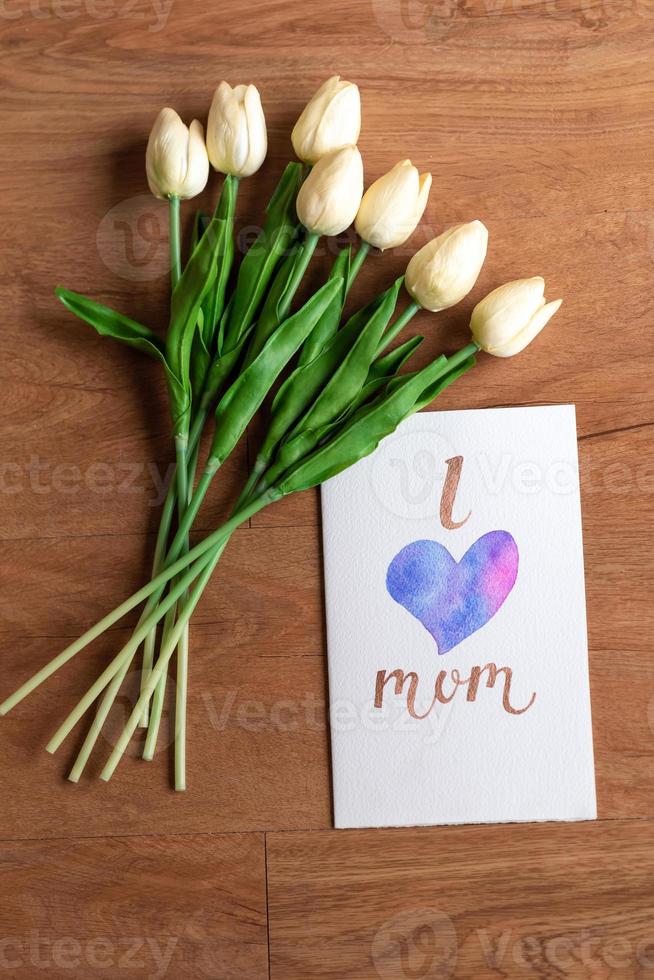 carta acquerello con parola amo mamma e fiore su pavimento in legno foto