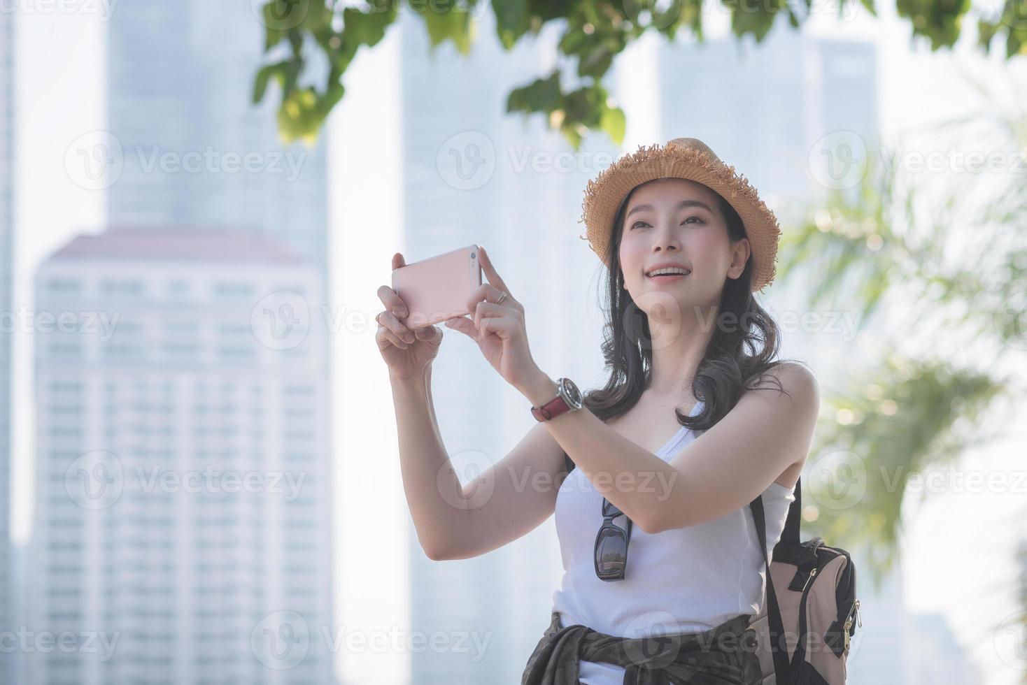 la bella donna turistica asiatica solista si diverte a scattare foto con lo smartphone in un punto turistico. viaggio di vacanza in estate