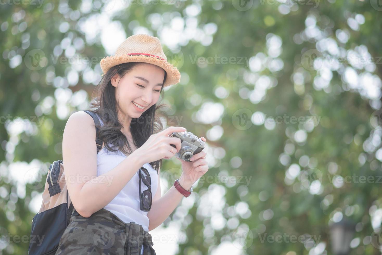 la bella donna asiatica turistica solista si diverte a scattare foto con la fotocamera retrò in un punto turistico. viaggio di vacanza in estate.