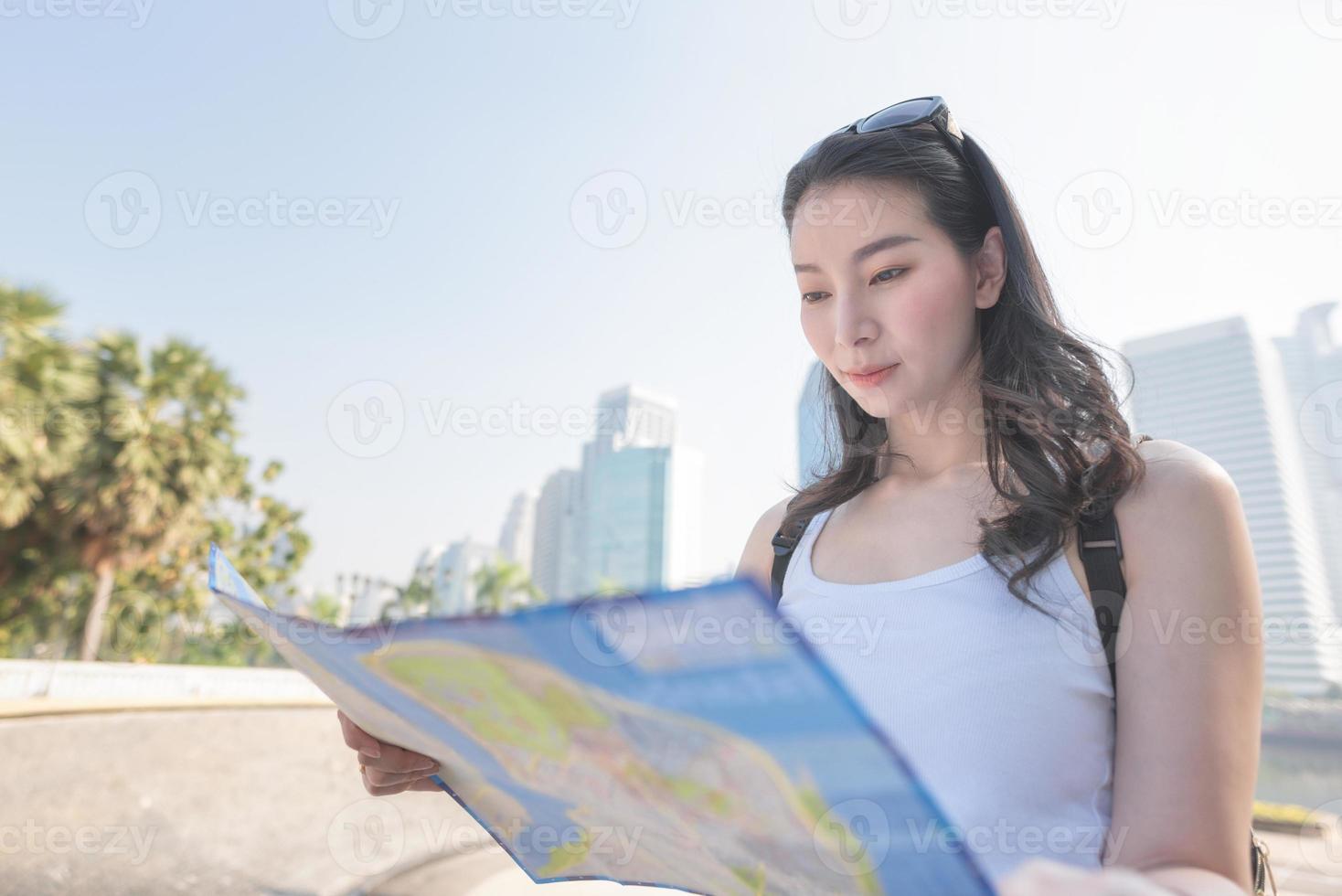 bella donna turistica asiatica guardando la mappa alla ricerca di luoghi turistici per i turisti. viaggio di vacanza in estate. foto