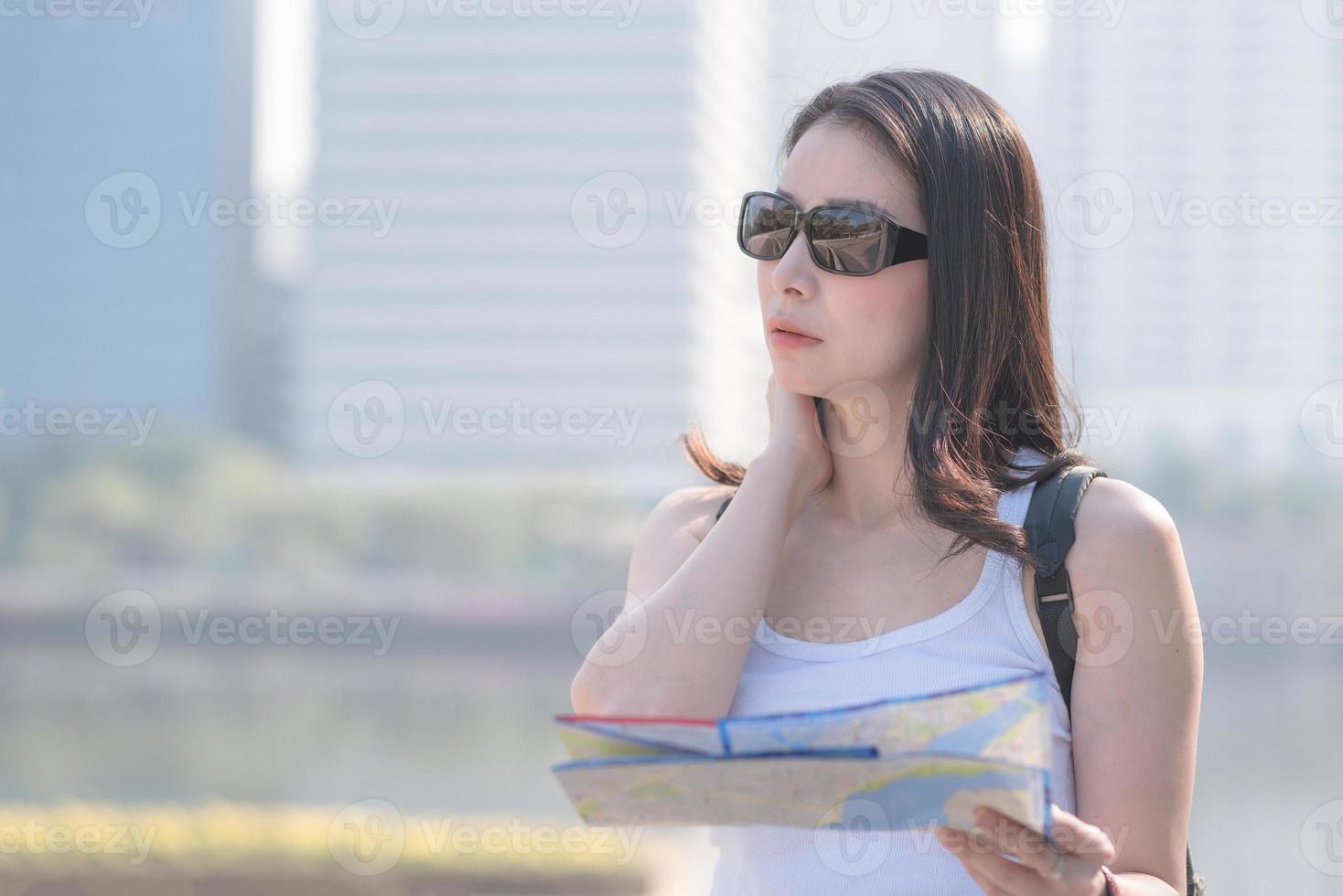 bella turista asiatica guardando la mappa alla ricerca di luoghi turistici per i turisti. viaggio di vacanza in estate. foto