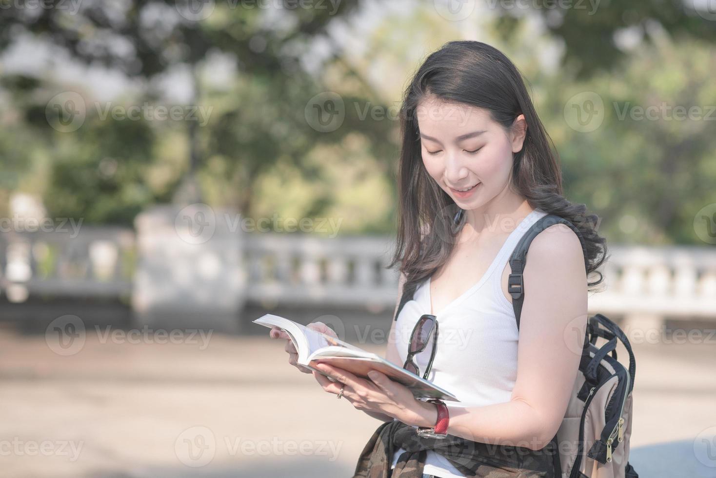 bella donna turistica asiatica che legge la guida di viaggio alla ricerca di luoghi turistici per i turisti. viaggio di vacanza in estate. foto