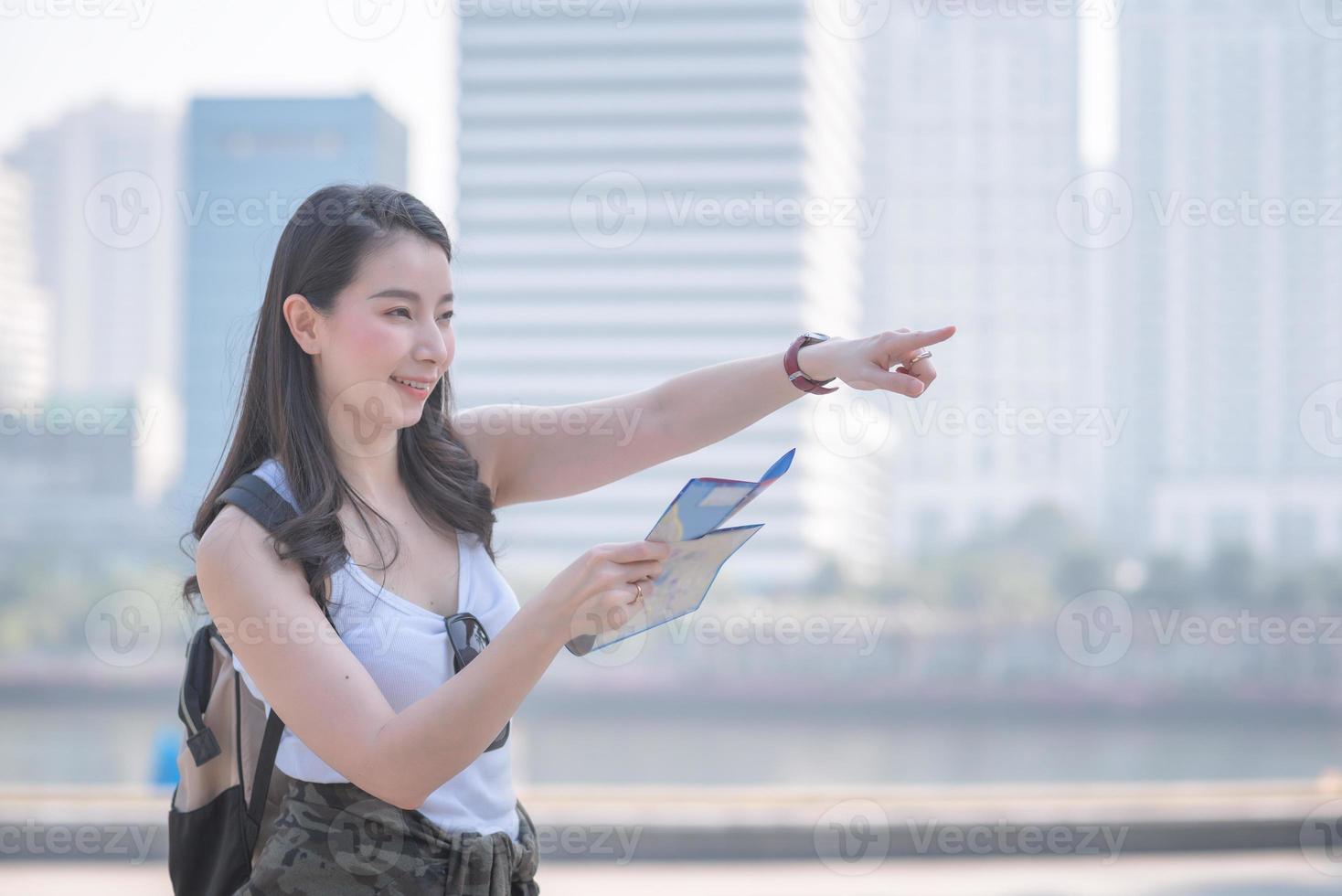 bella donna turistica asiatica guardando la mappa alla ricerca di luoghi turistici per i turisti. viaggio di vacanza in estate. foto