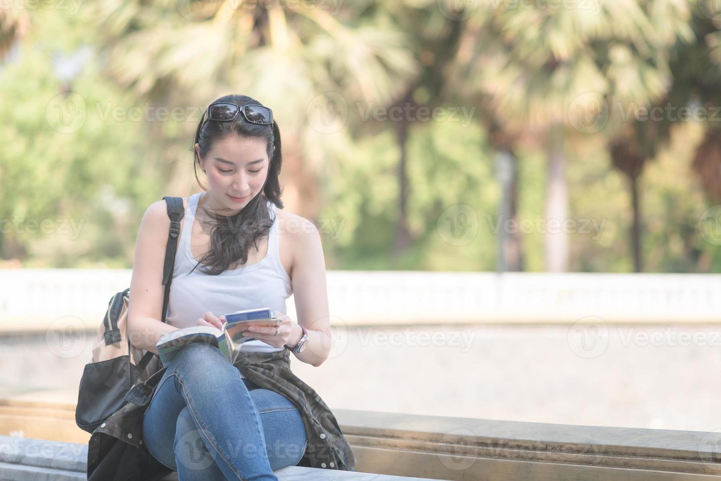 bella donna turistica asiatica che legge la guida di viaggio alla ricerca di luoghi turistici per i turisti. viaggio di vacanza in estate. foto