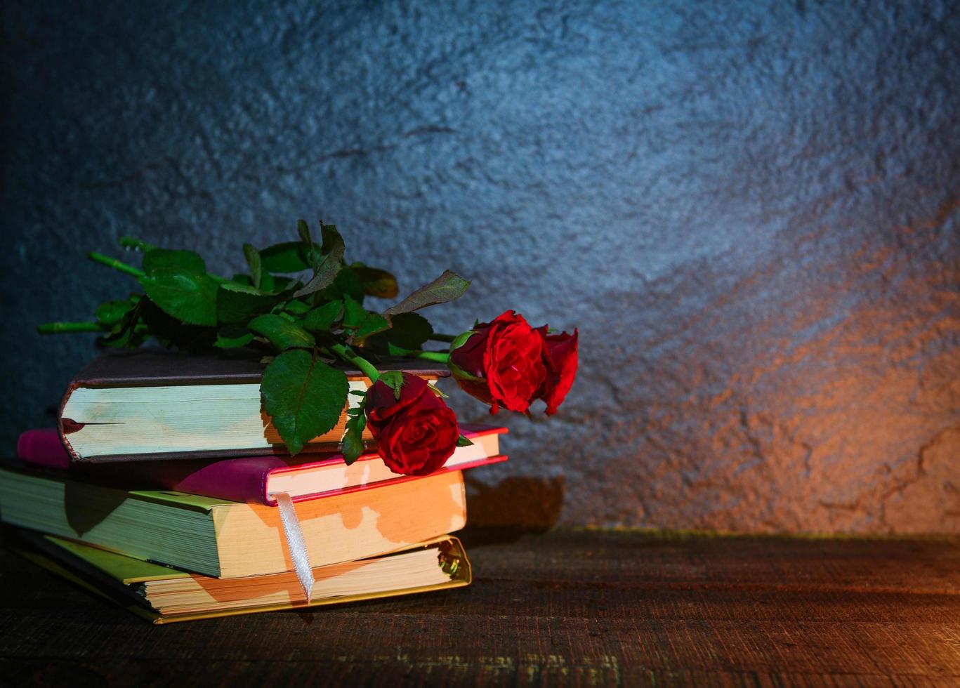 rosa rossa e libro amore educazione e amore nel concetto di scuola - fiori di natura morta su un vecchio libro sullo sfondo scuro foto