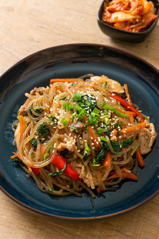 japchae o vermicelli coreani saltati in padella con verdure e maiale conditi con sesamo bianco foto