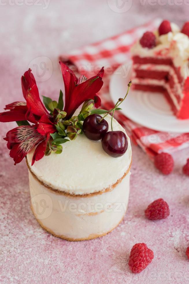 una piccola torta bianca e rosa decorata con fiori e frutti di bosco foto