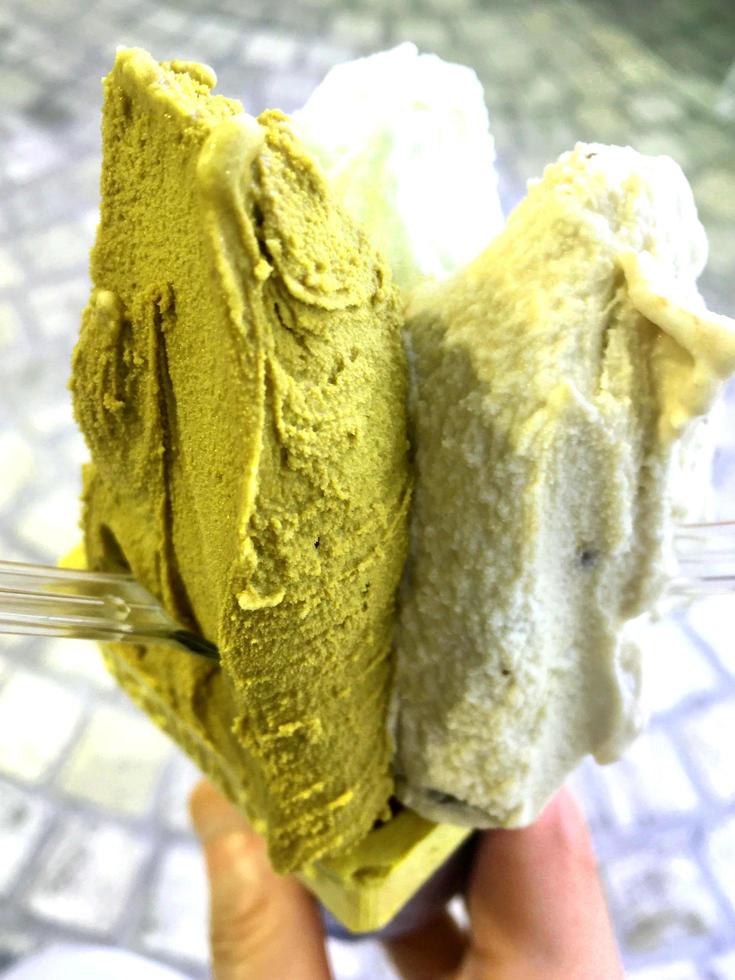 gelato sapore verde dessert congelato modello in mano tazza nera che tiene su legno. foto