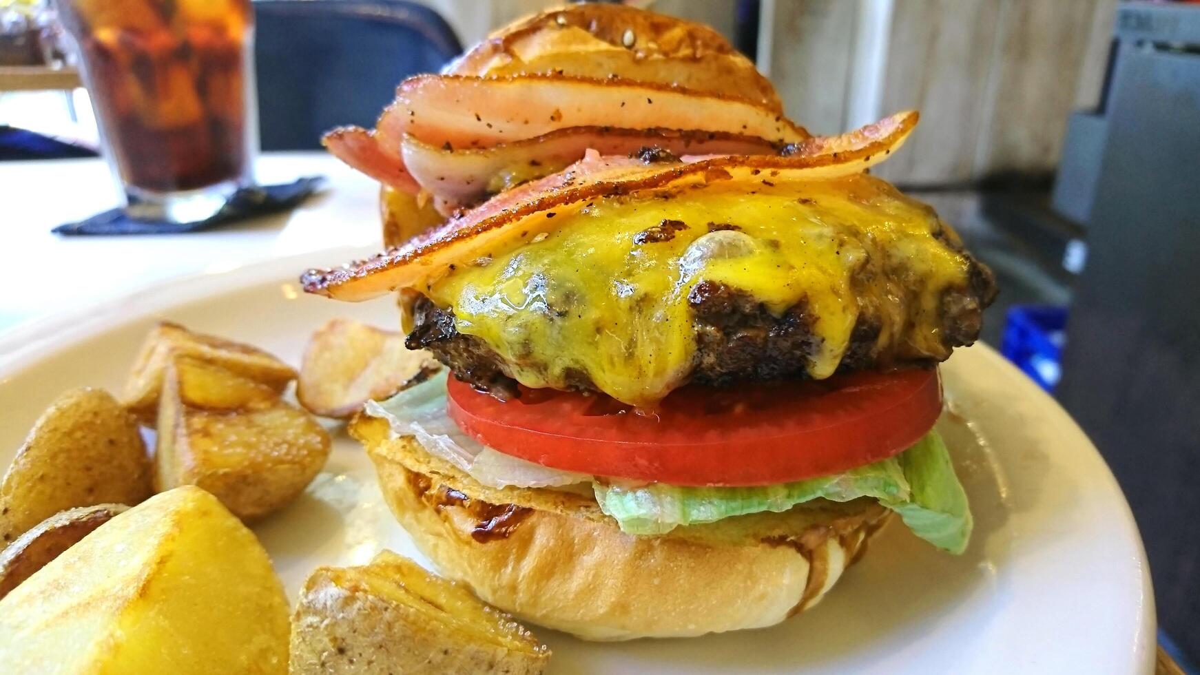 hamburger di manzo fresco cibo di strada con pane nero, verdure, uova, pancetta, formaggio e salse. foto