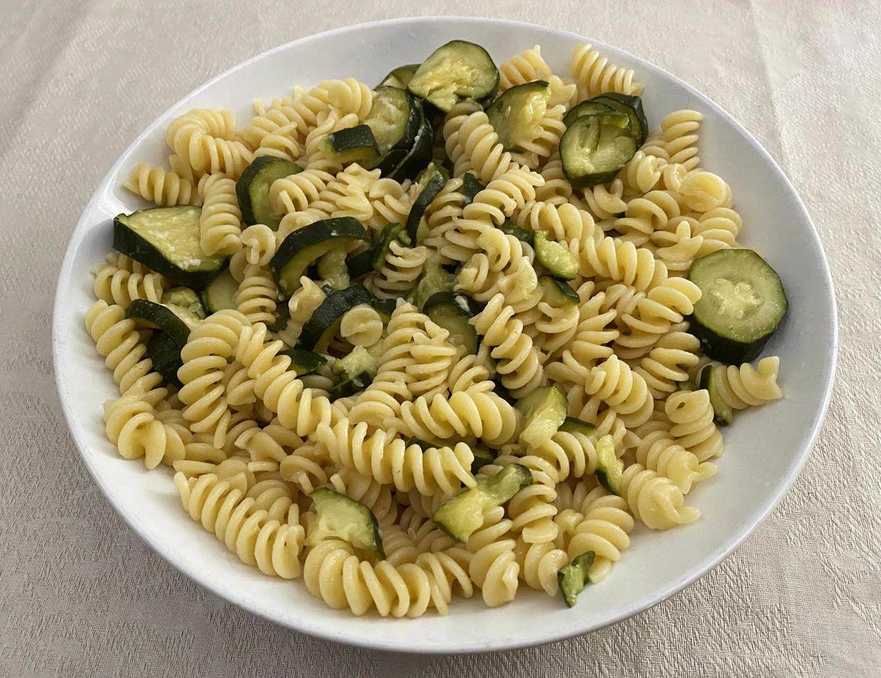 fusilli italiani con zucchine e olio d'oliva in un piatto bianco. cibo vegetariano e vegano. foto