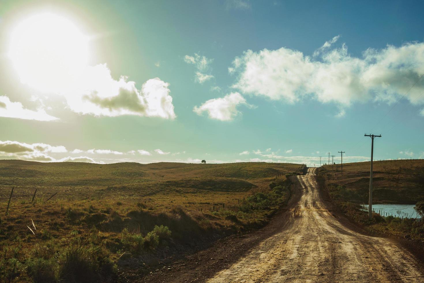 strada sterrata deserta che passa attraverso pianure rurali chiamate pampa con colline verdi e luce solare vicino a cambara do sul. una piccola cittadina di campagna nel sud del Brasile con incredibili attrazioni turistiche naturali. foto