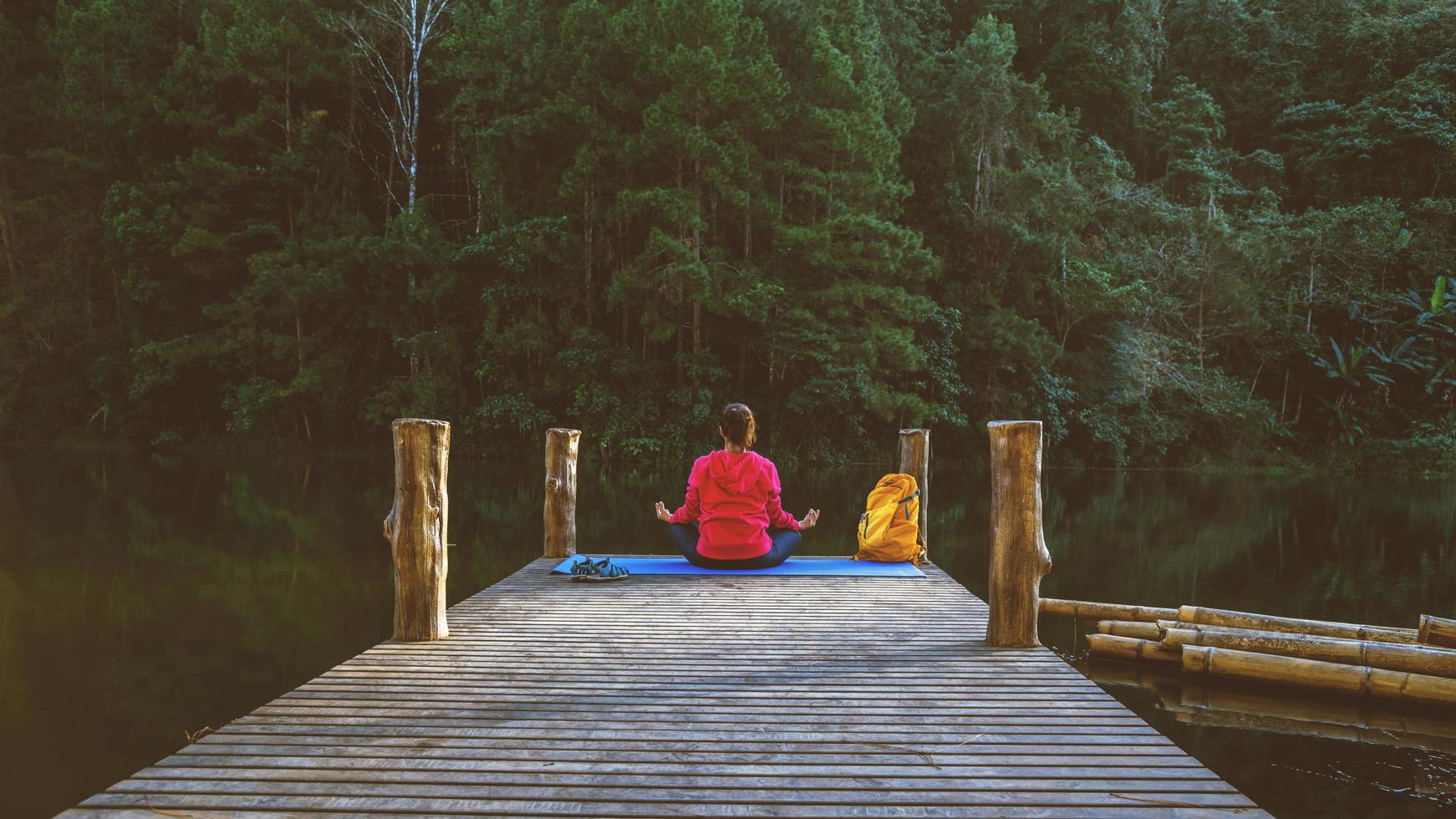 le donne asiatiche si rilassano durante le vacanze. gioca se lo yoga. sulla montagna, esercitarsi, giocare se yoga sul ponte di bambù accanto al lago nella nebbia a pang ung, thailandia. foto