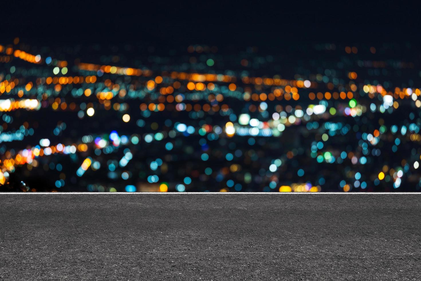 strada asfaltata con linee di marcatura strisce bianche texture con sfondo notturno di luce bokeh di città. foto