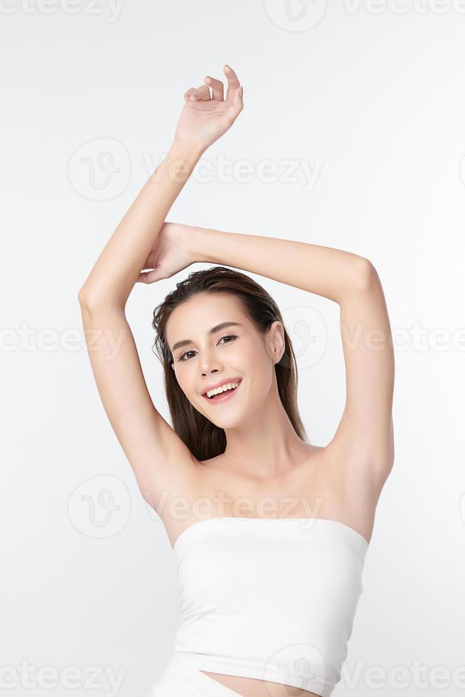 bella giovane donna asiatica che alza le mani per sfoggiare ascelle o ascelle pulite e igieniche su sfondo bianco, pulizia delle ascelle liscia e concetto di protezione foto