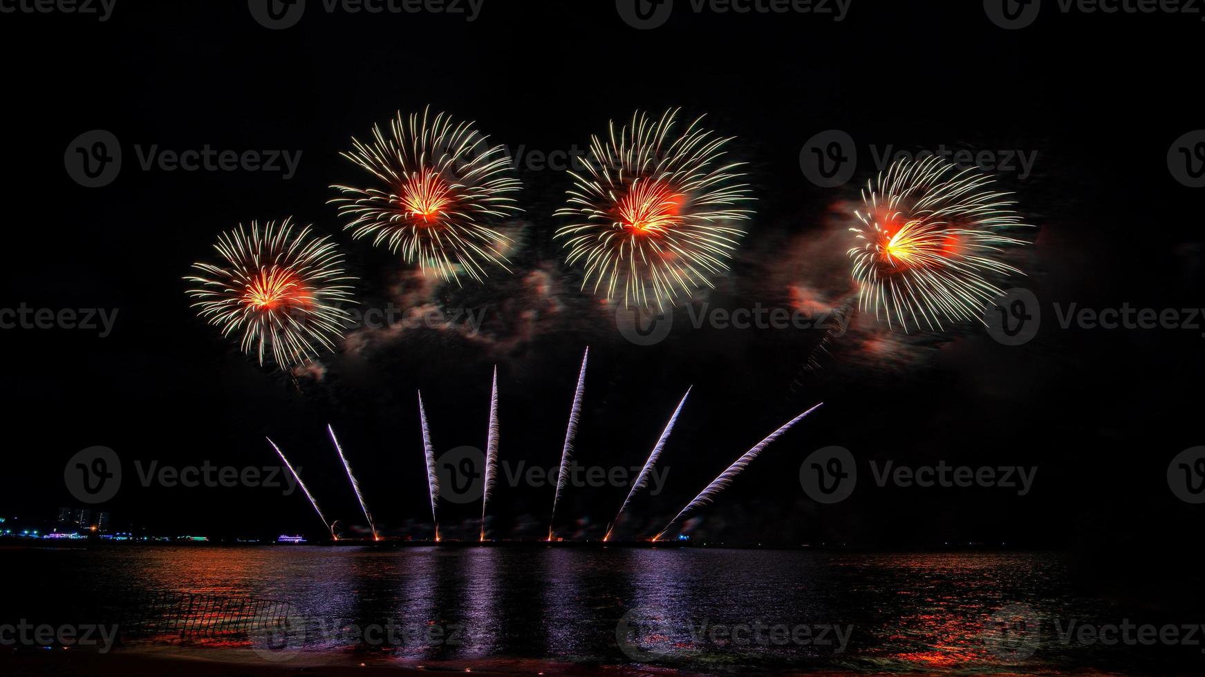 incredibile bellissimo spettacolo pirotecnico colorato nella notte di celebrazione, che mostra sulla spiaggia del mare con multi colore di riflessione sull'acqua foto